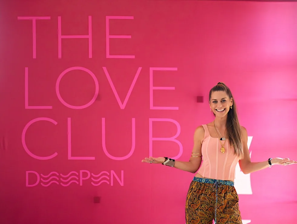 Christina Weber in front of the Love Club sign at a WeDeepen event