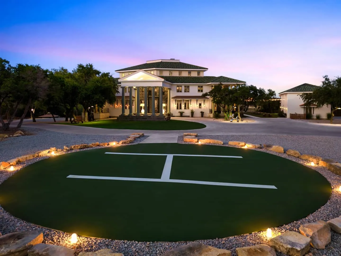 The Gatsby Mansion at dusk, lit up from the front lawn